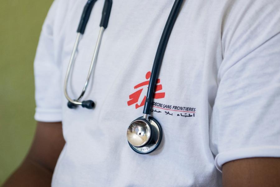 Close-up of a person wearing an MSF t-shirt with a stethoscope hanging around his neck (where the photo is cut so no face is visible)