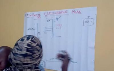 Une mère déplacée dessine le plan d‘accès à son centre de santé – Mora